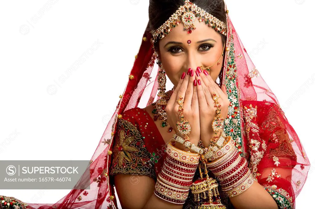 Indian bride in traditional wedding dress covering his face
