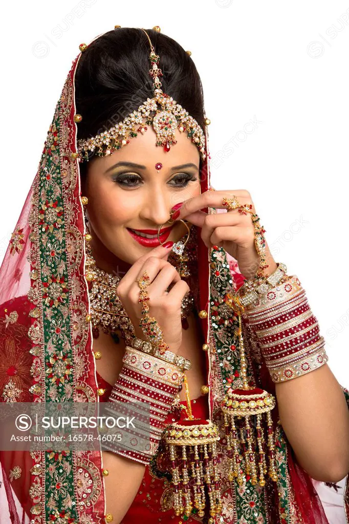 Indian bride in traditional wedding dress adjusting her nose ring