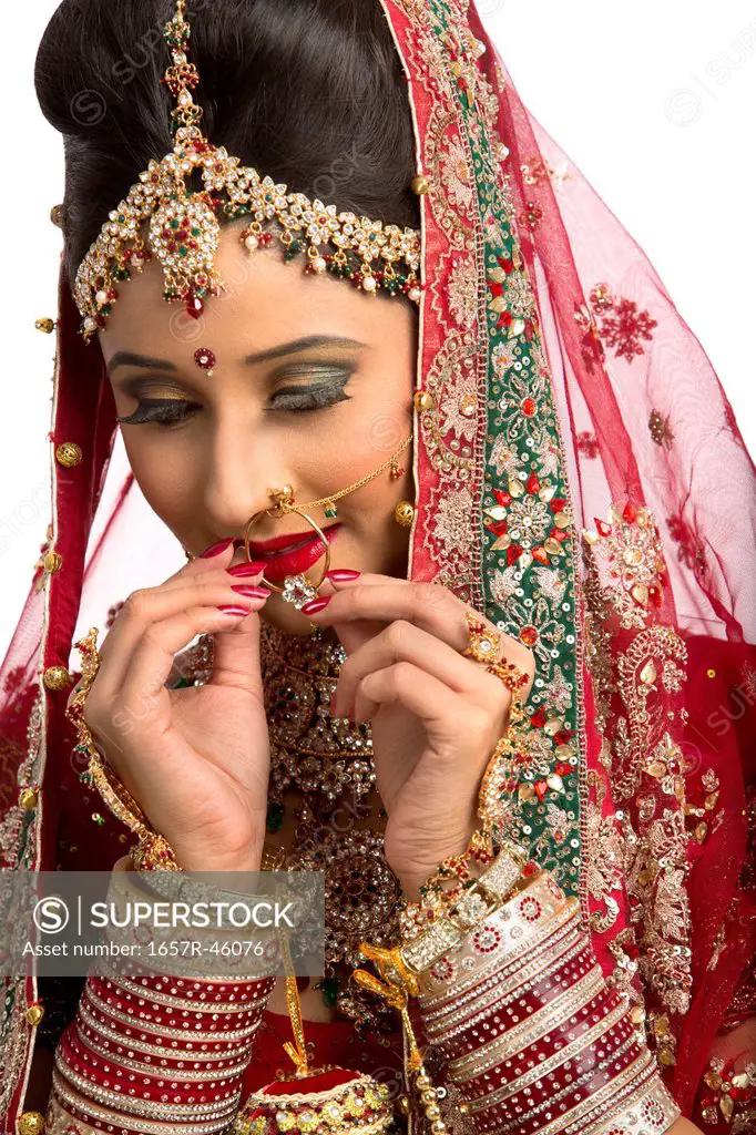 Indian bride in traditional wedding dress adjusting her nose ring