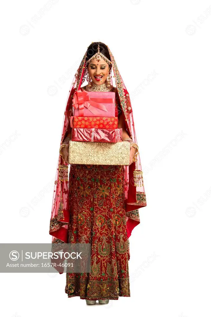 Smiling Indian bride in traditional wedding dress holding gifts