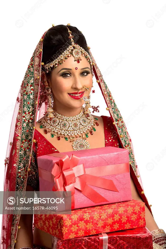 Smiling Indian bride in traditional wedding dress holding gifts