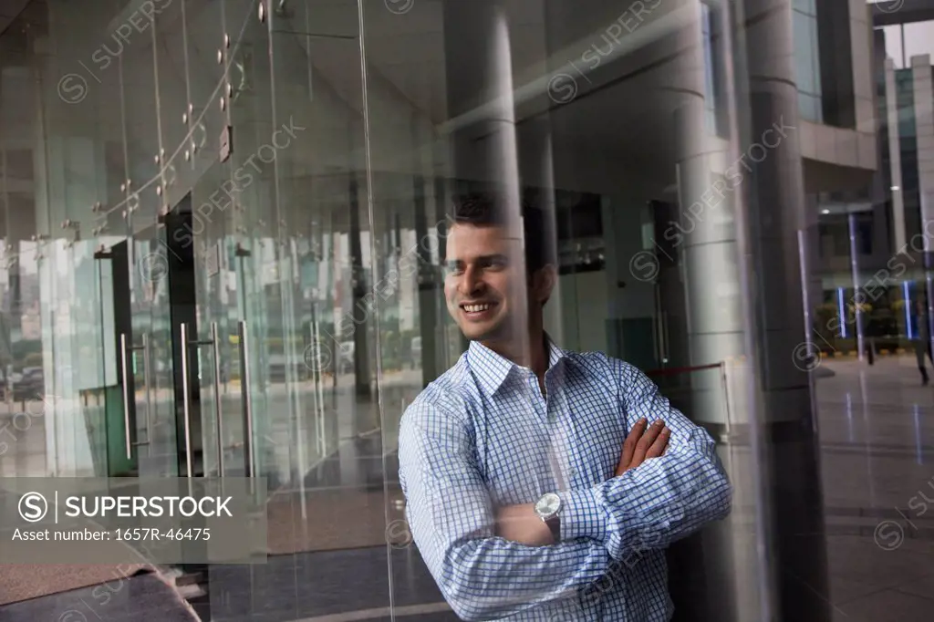 Businessman leaning against a glass wall in office