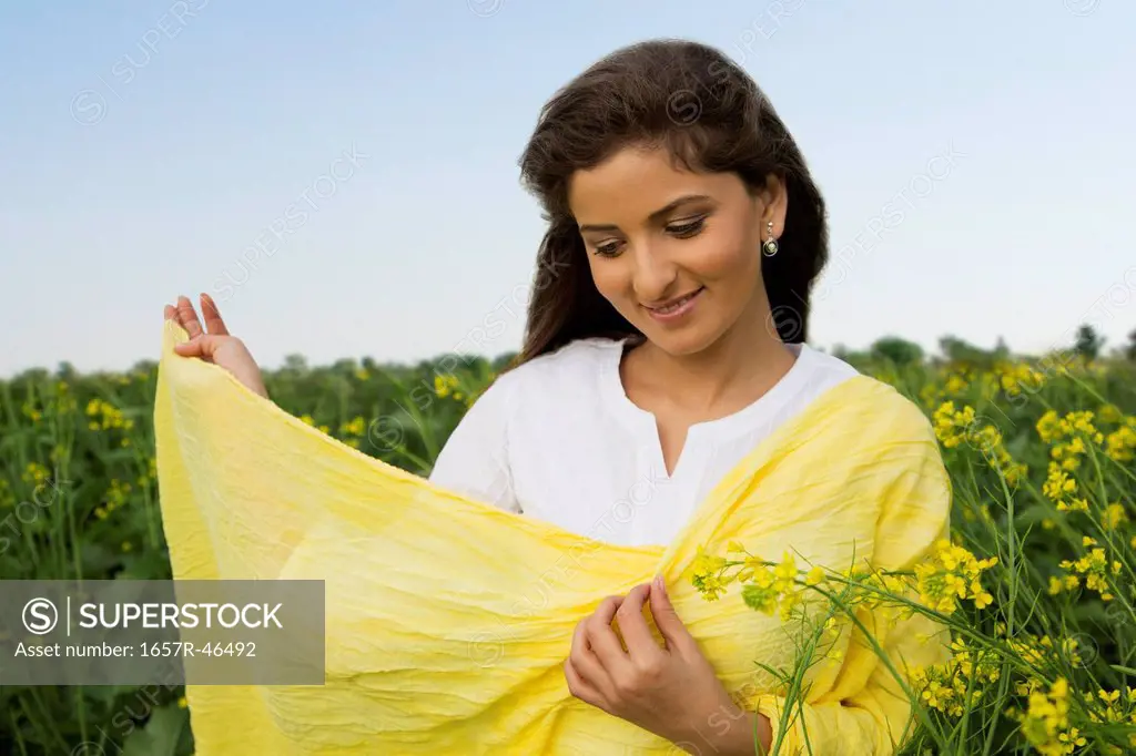 Woman standing in a mustard field and smiling