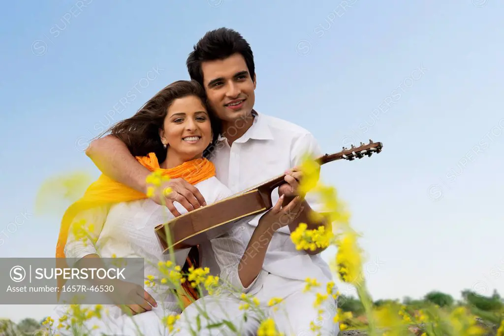 Couple sitting in a field with a mandolin