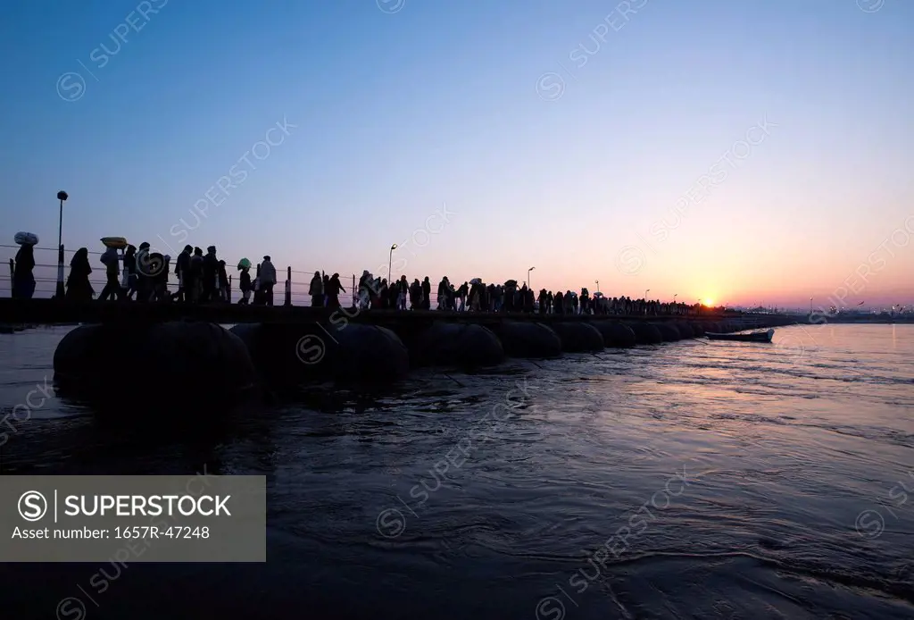 Pilgrims walking over a bridge during sunrise at Maha kumbh, Allahabad, Uttar Pradesh, India