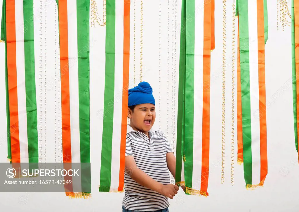 Boy standing near tricolor scarf's and laughing