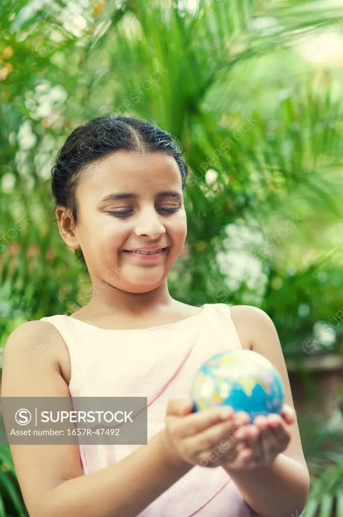 Close-up of a smiling girl holding a globe