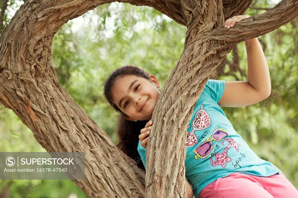 Girl playing on a tree in a park