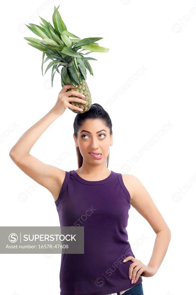 Woman carrying a pineapple on her head and making a funny face