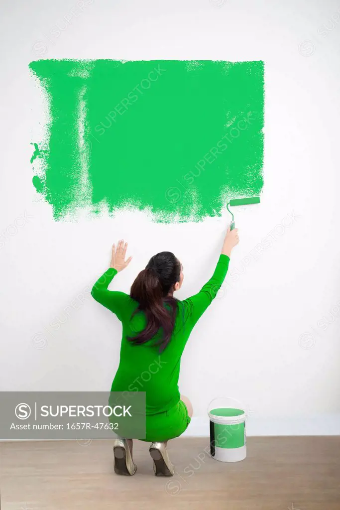 Woman painting a wall with a green color