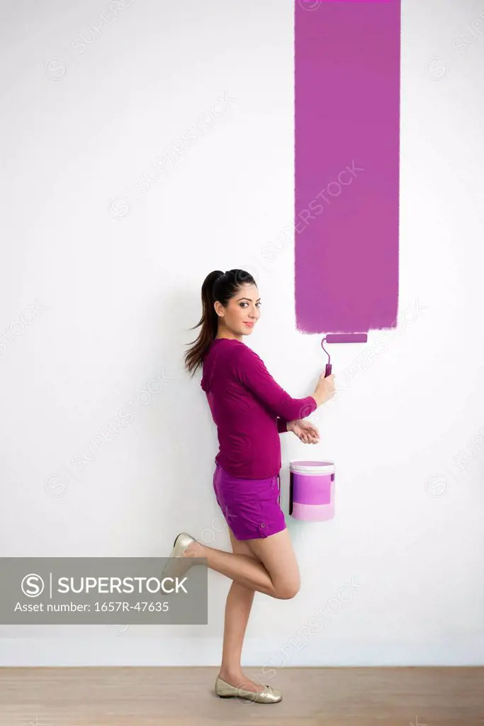 Woman painting a wall with a purple color
