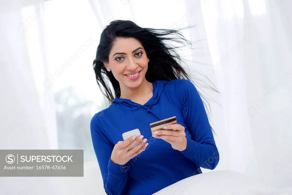 Portrait of a woman holding a mobile phone and credit card