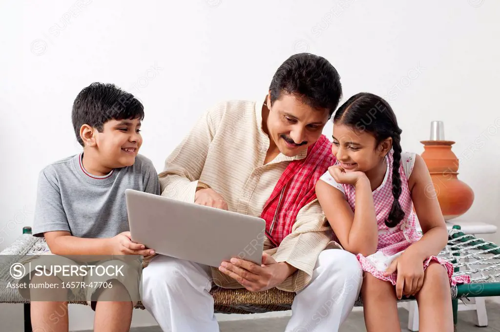 Farmer using a laptop with his children