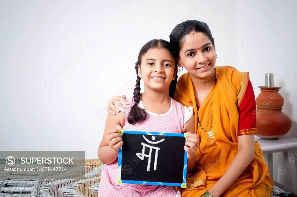 Portrait of a woman with her daughter holding a slate with word Maa written on it