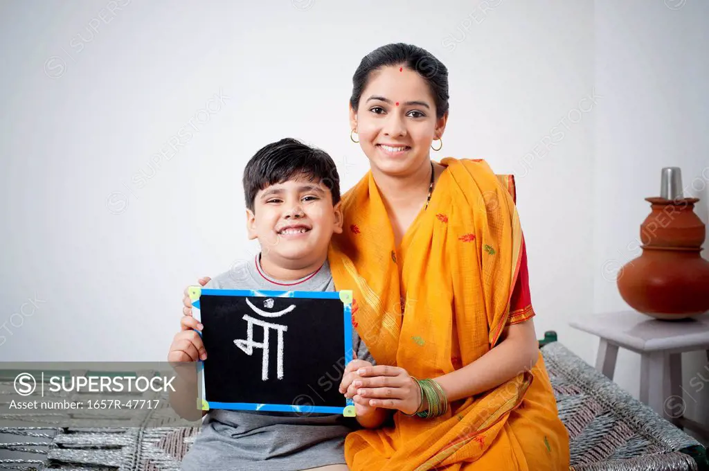 Portrait of a woman sitting with her son holding a slate with word Maa written on it