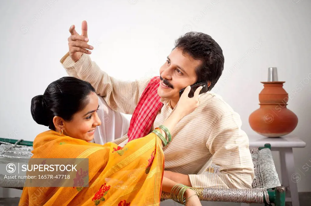 Man talking on a mobile phone hold by his wife