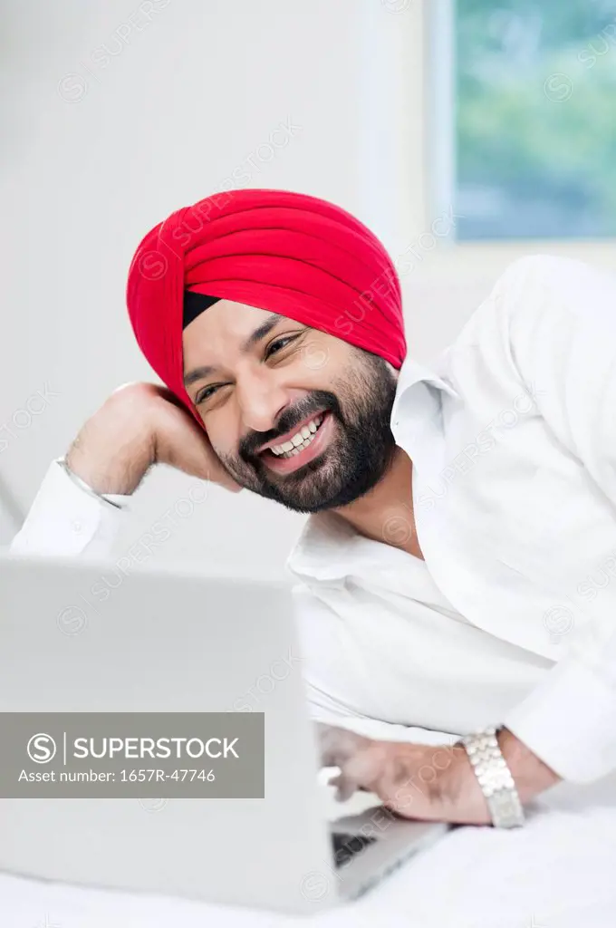 Sikh man using a laptop and smiling