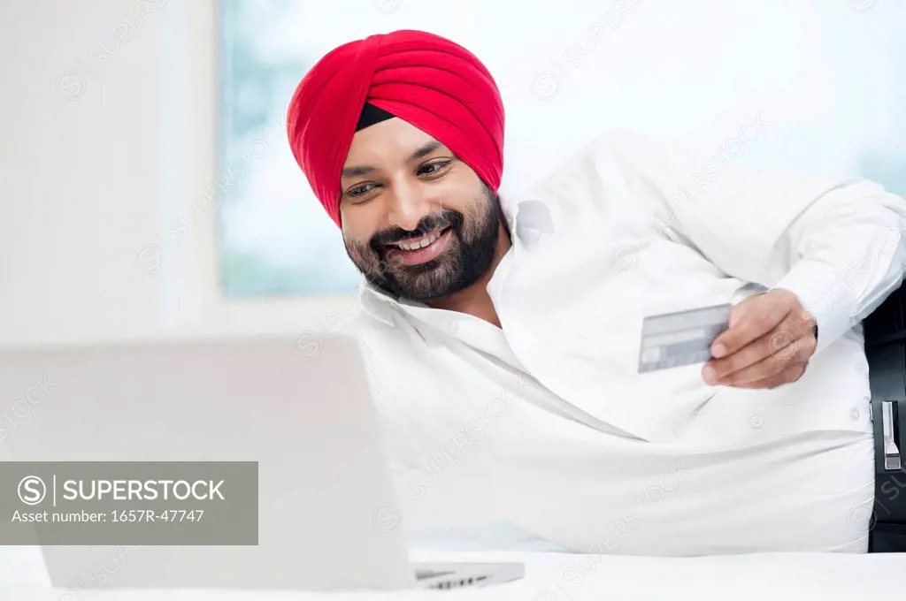 Sikh man doing online shopping with a credit card