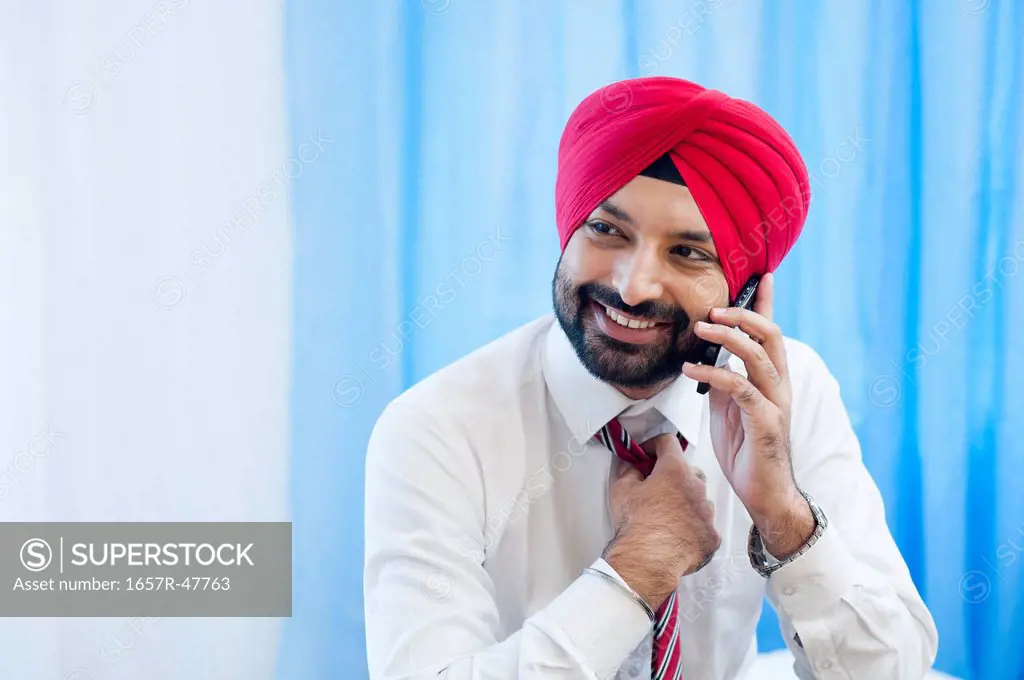 Businessman adjusting his tie and talking on a mobile phone