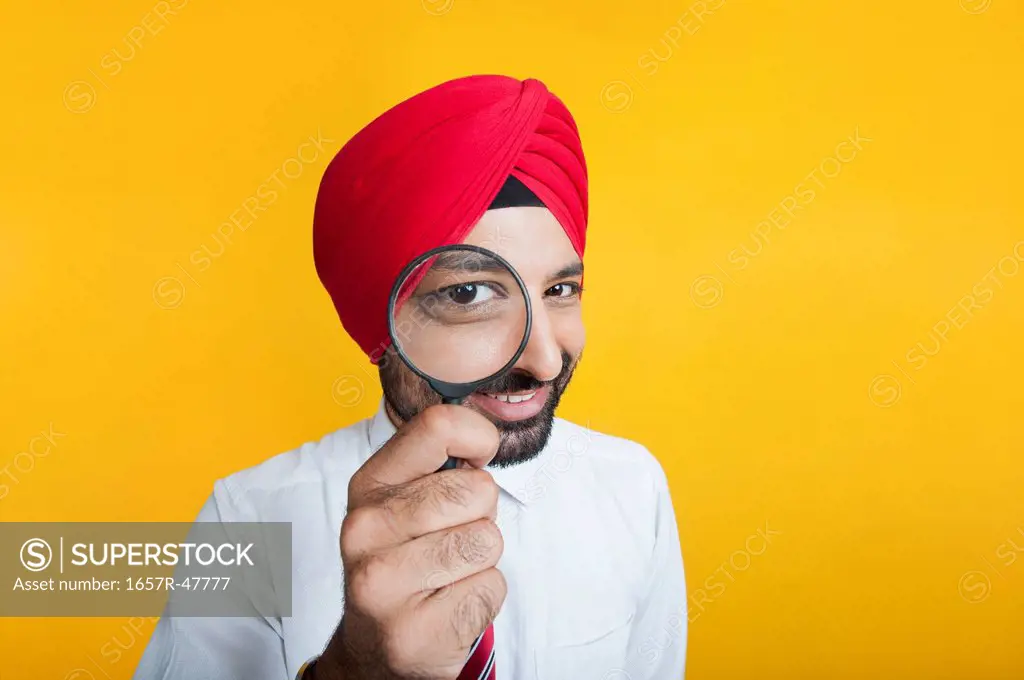 Portrait of a businessman looking through magnifying glass