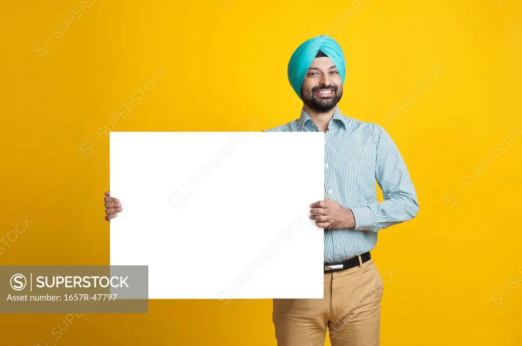 Portrait of a sikhman holding a blank placard and smiling