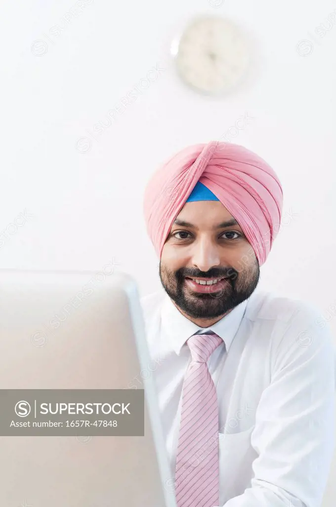 Portrait of a businessman sitting in front of a computer and smiling