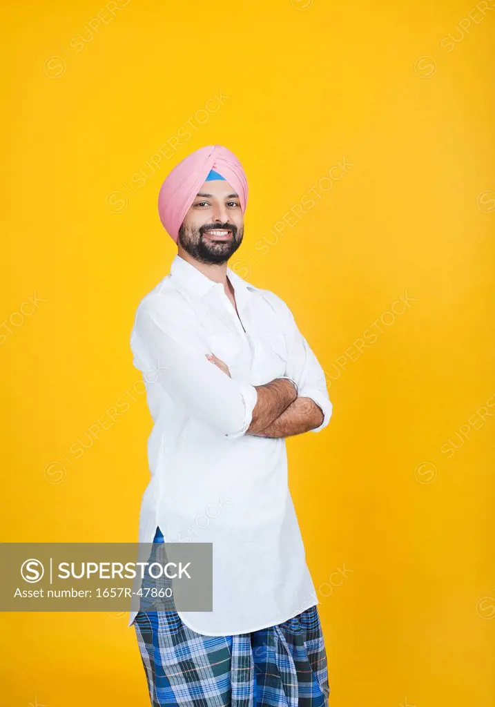Portrait of a Sikh man standing with his arms crossed and smiling