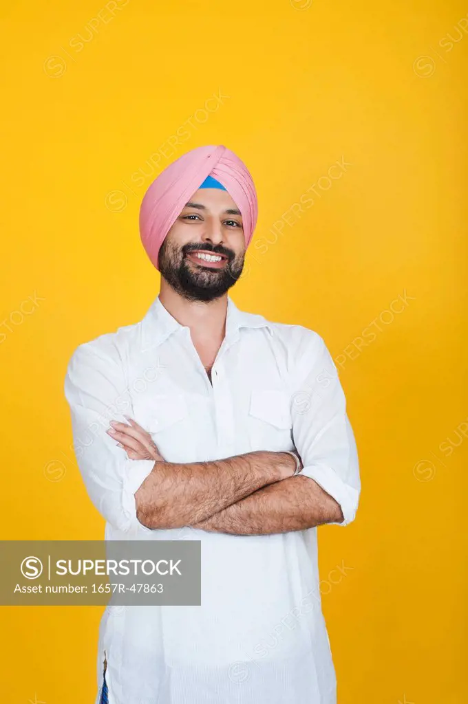 Portrait of a Sikh man standing with his arms crossed and smiling