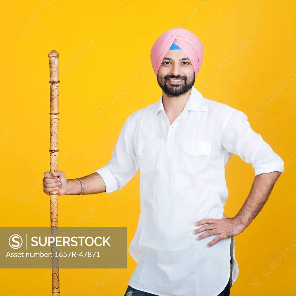 Portrait of a Sikh man holding wooden staff and smiling