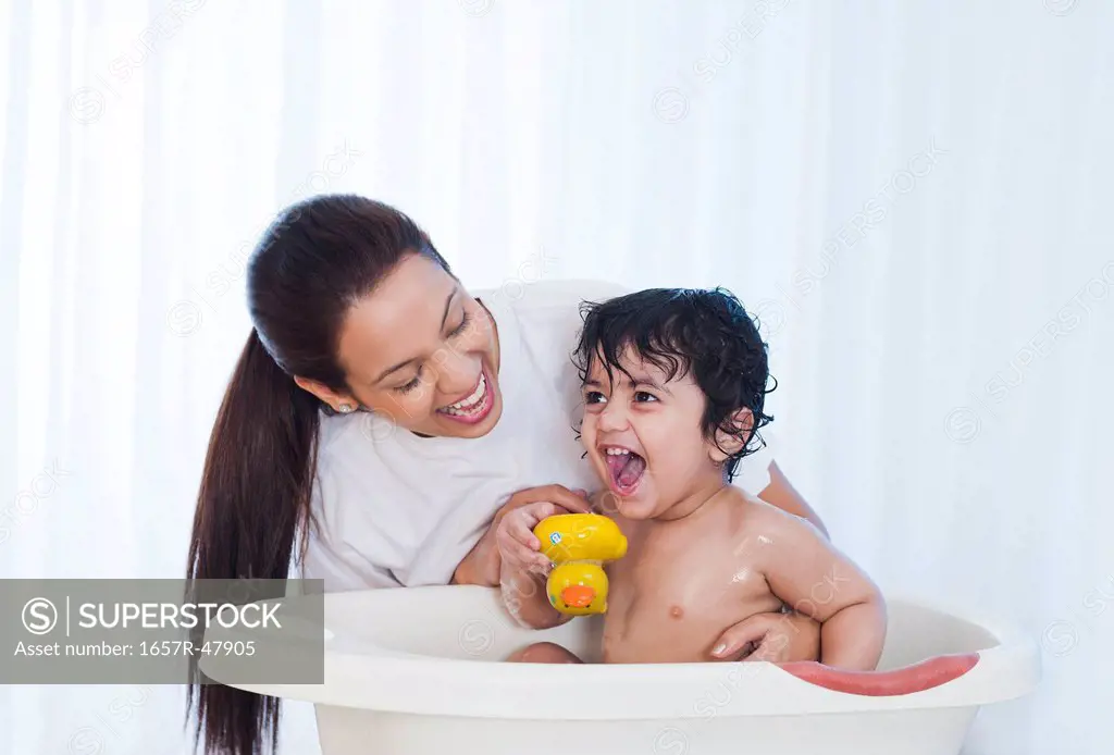 Woman giving bath to her son and smiling