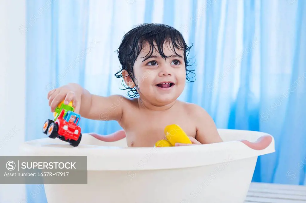 Baby boy playing with toys in a bathtub