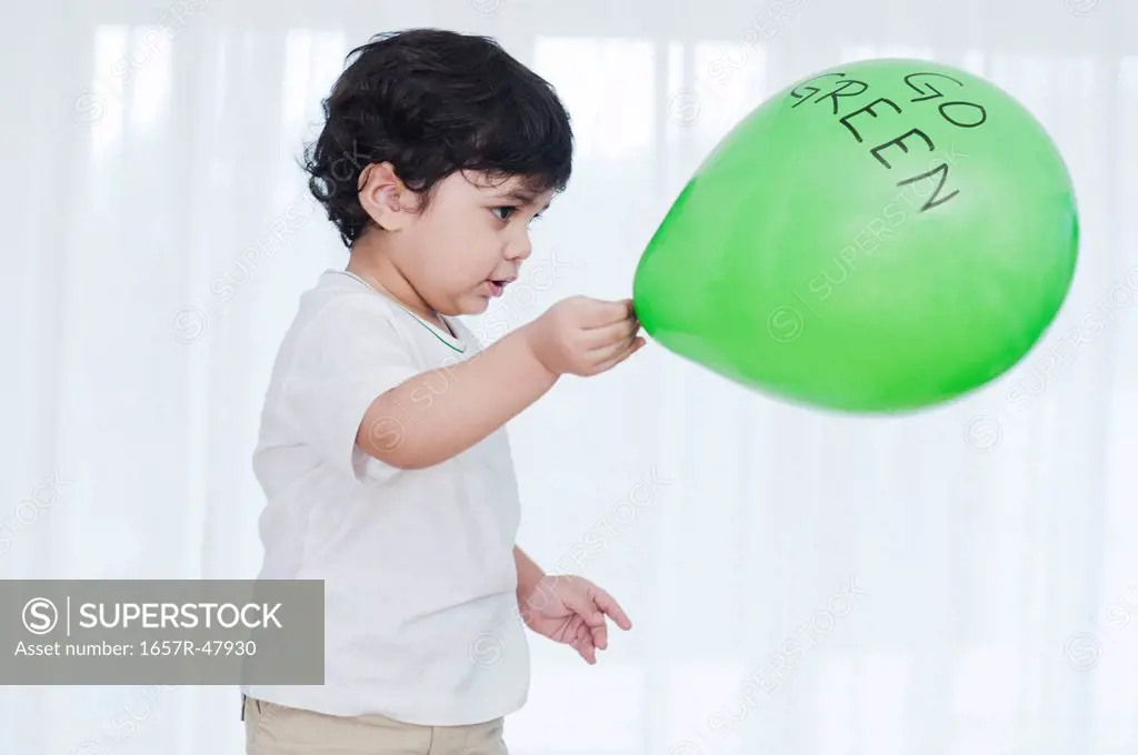 Baby boy playing with a green balloon