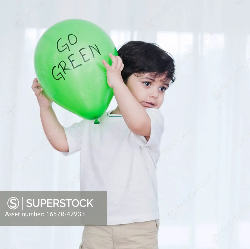 Baby boy playing with a green balloon