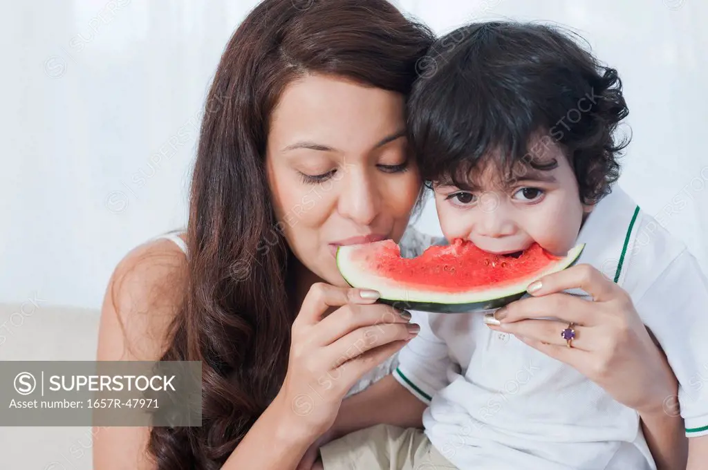 Close-up of a woman and her son eating watermelon