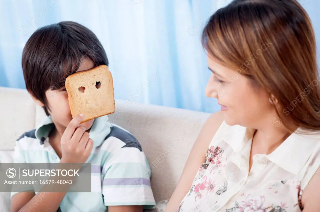 Boy looking at his mother through the holes of a bread