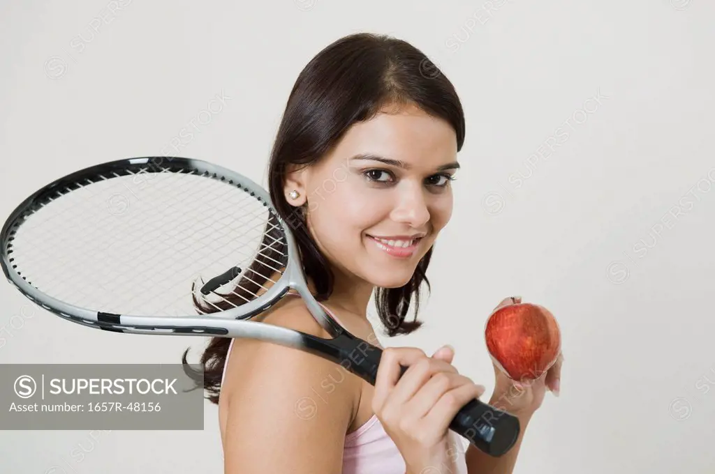 Woman holding an apple and a tennis racket