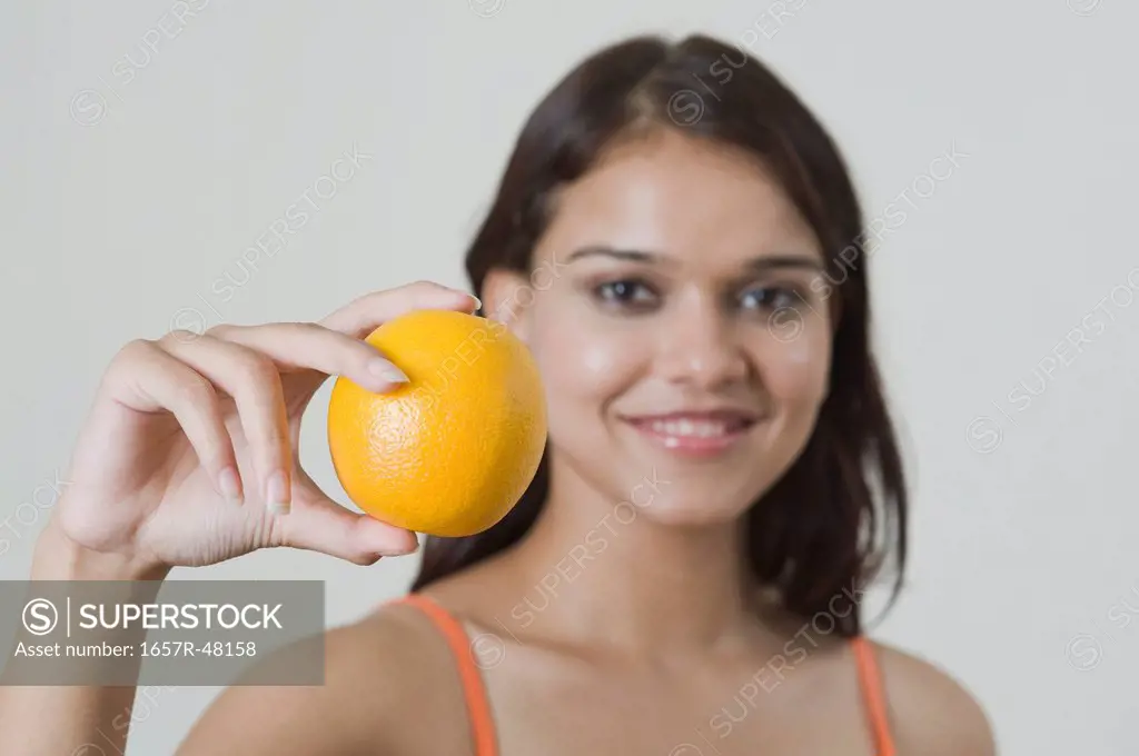 Portrait of a woman holding an orange and smiling