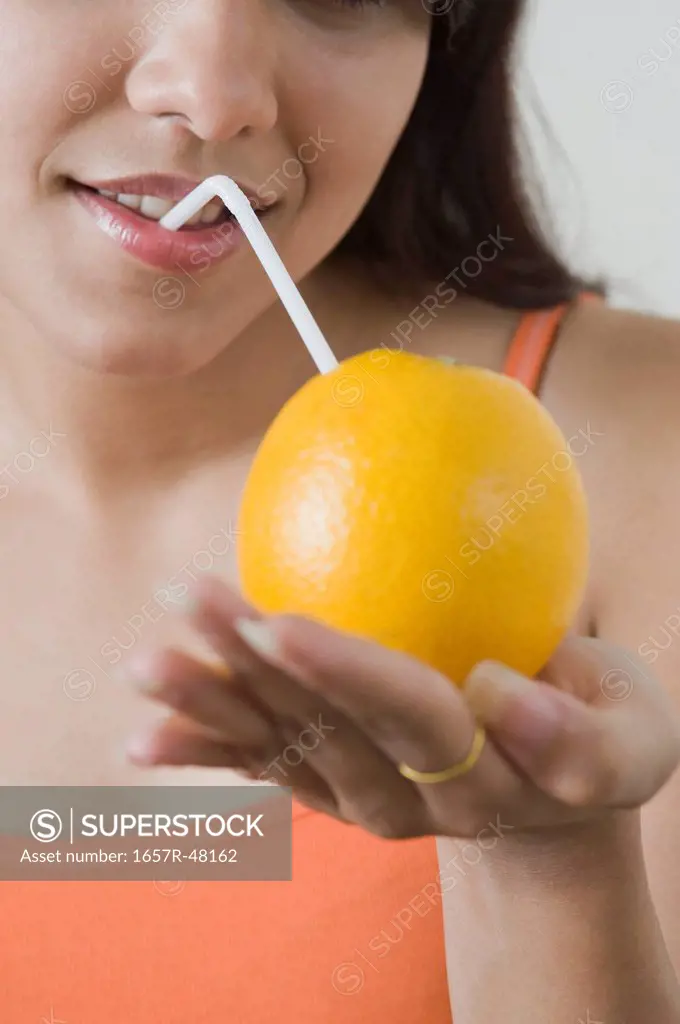 Woman drinking orange juice with a straw