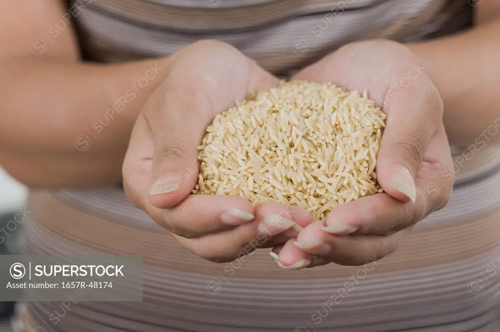 Mid section view of a woman holding brown rice
