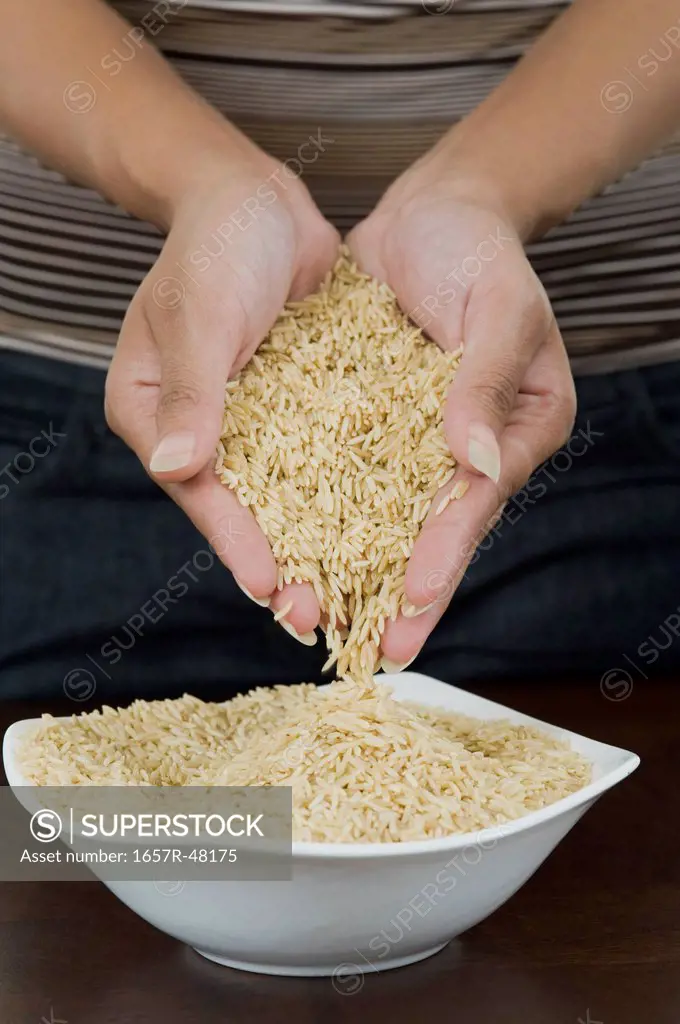 Mid section view of a woman pouring brown rice in a bowl