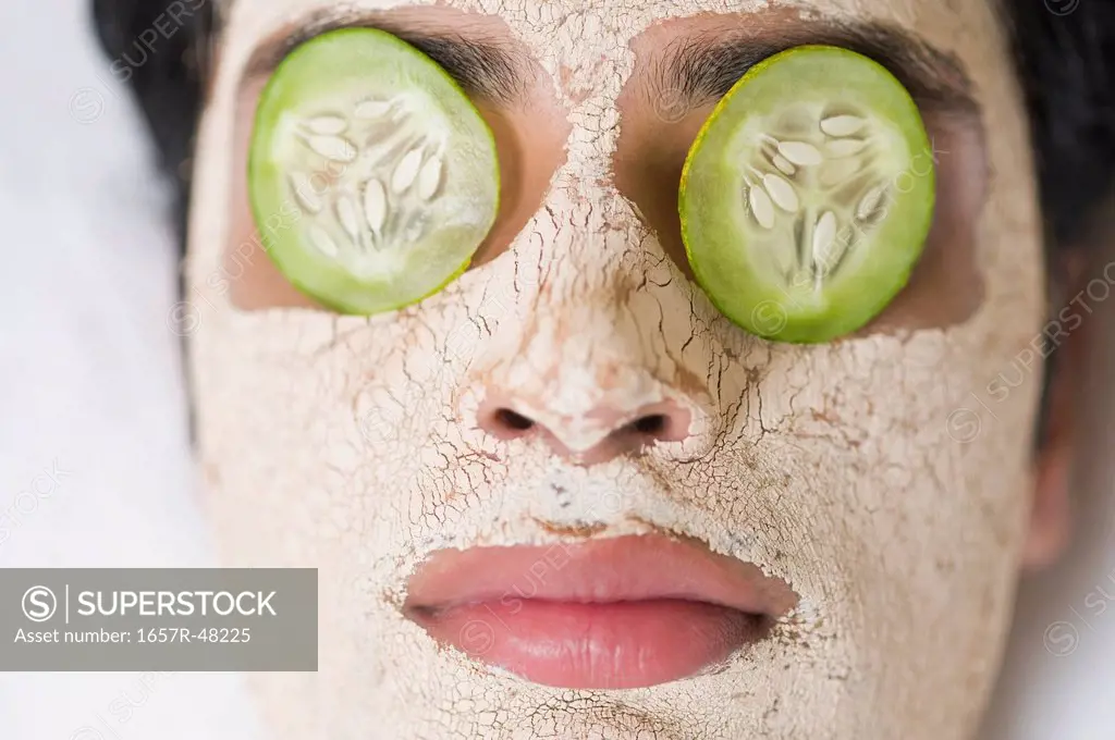 Close-up of a man with facial mask and cucumber slices on eyes