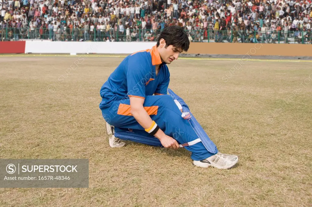 Cricket player adjusting his shin guard