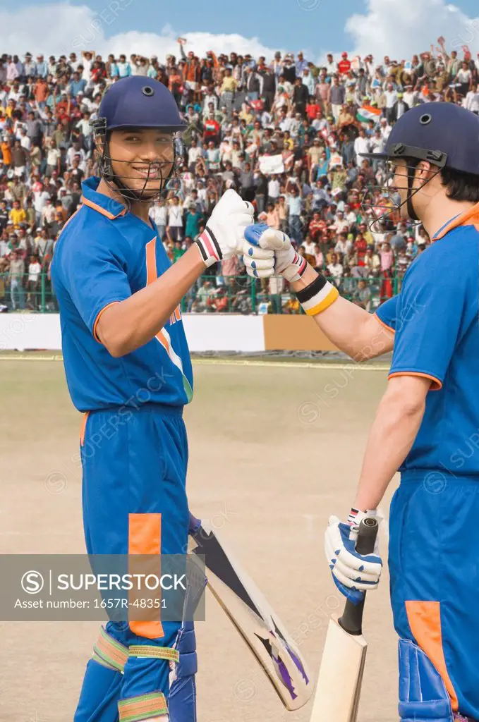 Two cricket batsmen fist bumping each other