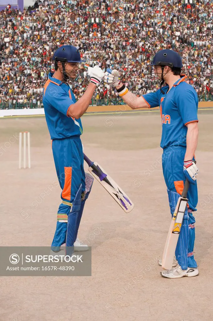 Two cricket batsmen fist bumping each other