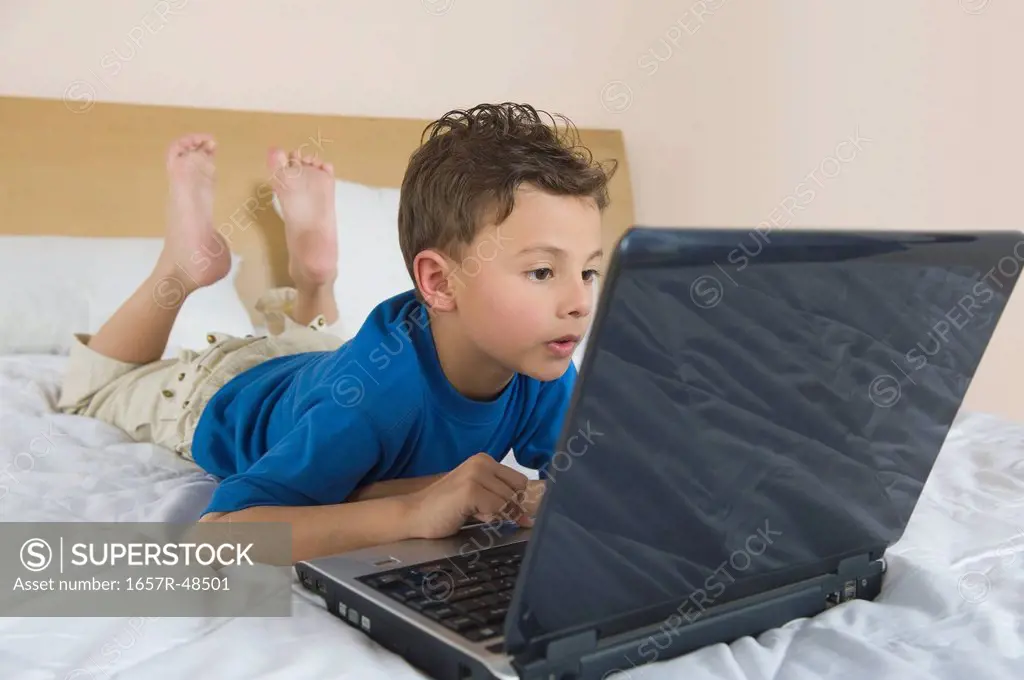 Boy using a laptop on the bed