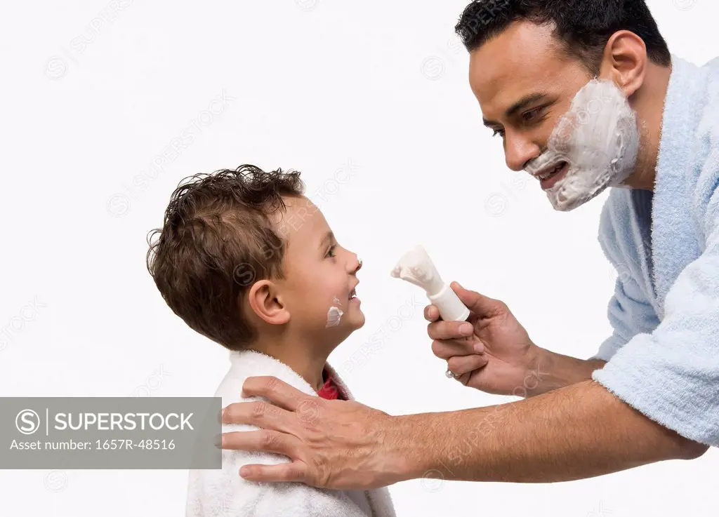 Man applying shaving cream on his son's face