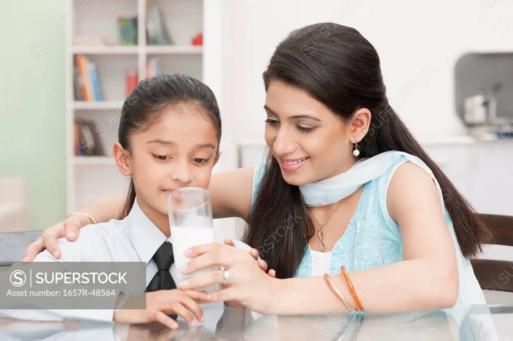 Woman giving a glass of milk to her daughter