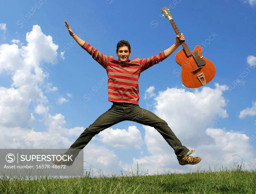 Man holding a guitar and jumping, Gurgaon, Haryana, India