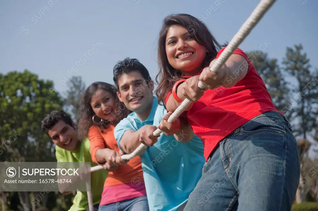 Friends playing tug-of-war in a garden