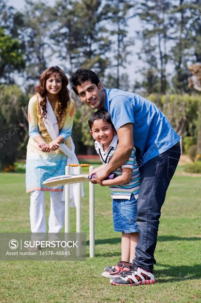 Couple playing cricket with their son, Gurgaon, Haryana, India